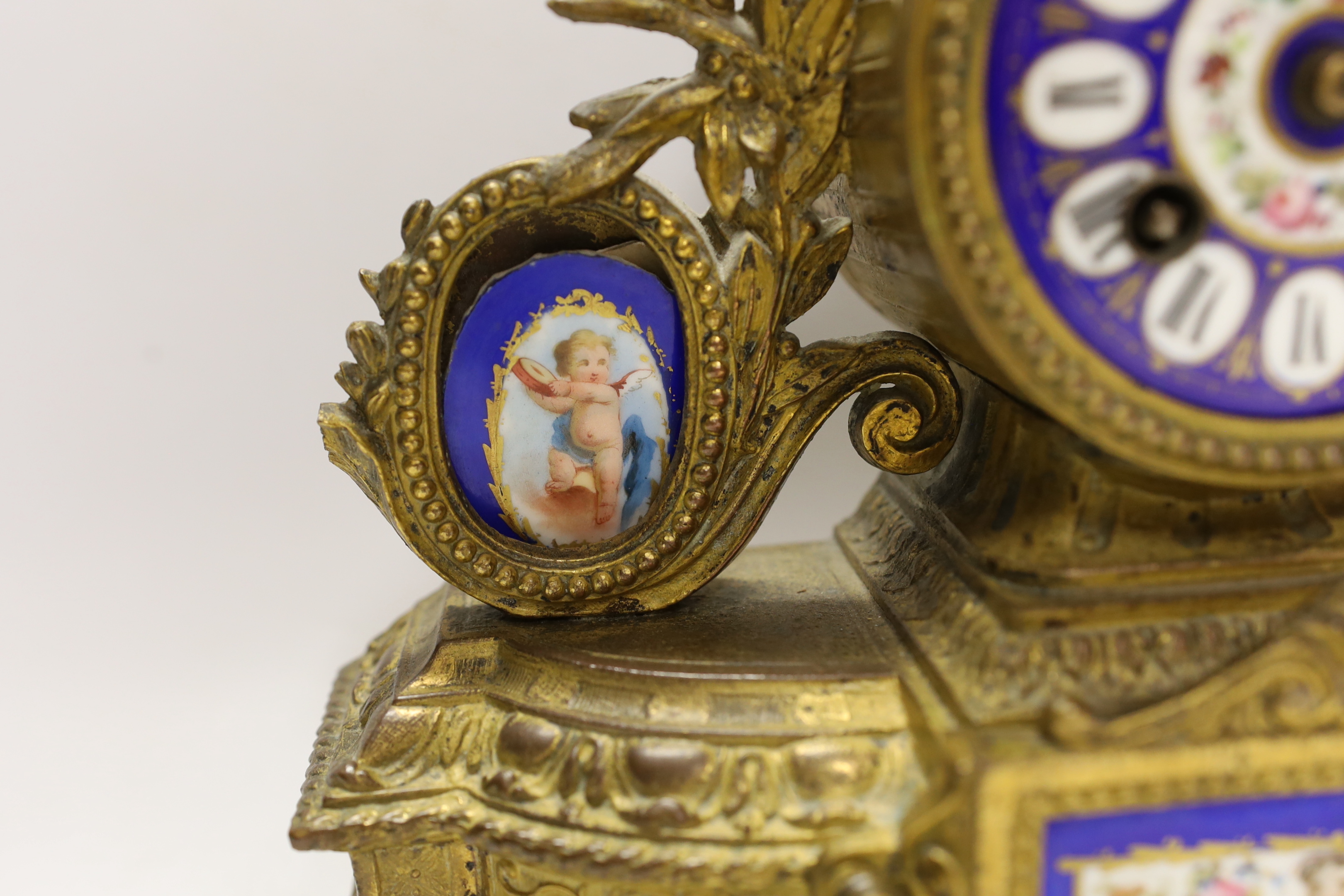 A 19th century ornate French gilt brass and porcelain clock, with two matching two branch candelabra garnitures, clock 31cm high